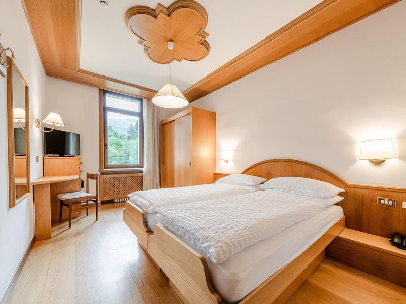 Chambre d'hôtel lumineuse avec lit double, bureau et fenêtre donnant sur la verdure.