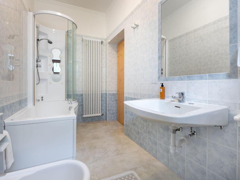 Salle de bain lumineuse avec baignoire, cabine de douche, lavabo et grand miroir.