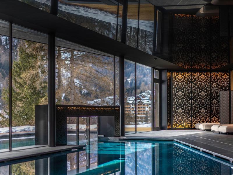 Intérieur d'une piscine d'hôtel de luxe avec grandes fenêtres et vue sur la montagne
