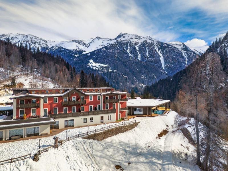 Hôtel dans un paysage montagneux enneigé avec des sommets enneigés et un ciel nuageux.