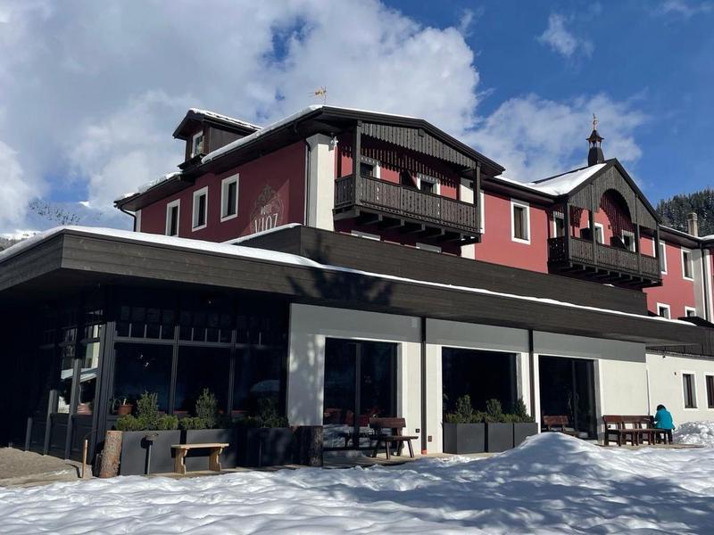 Bâtiment d'hôtel dans un paysage montagneux enneigé sous un ciel nuageux.