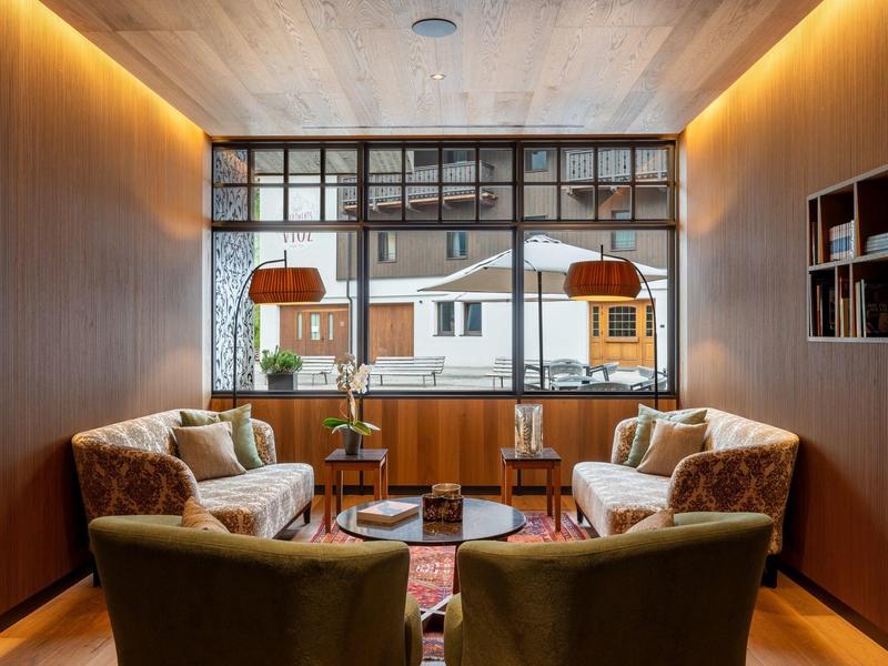 Espace détente confortable avec fauteuils et canapés devant une grande fenêtre d'hôtel.