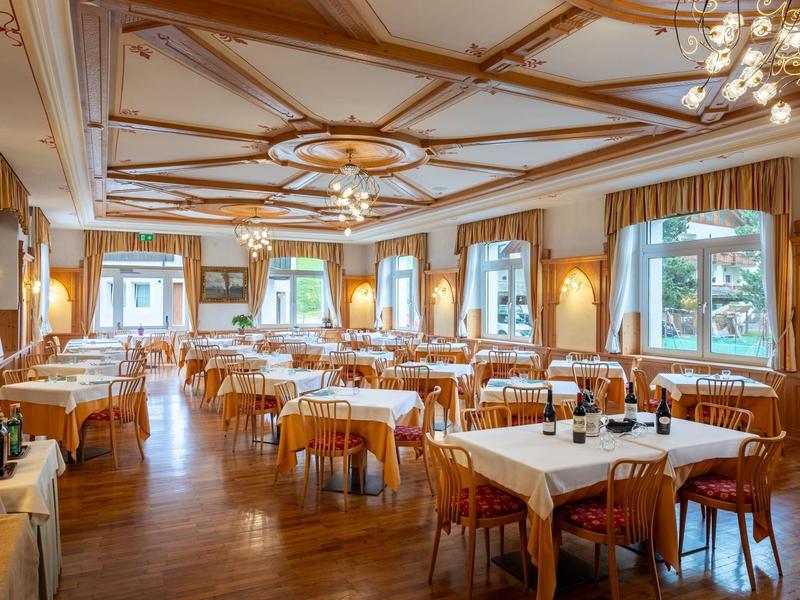 Grande salle à manger élégamment meublée avec des tables dressées et un plafond en bois.