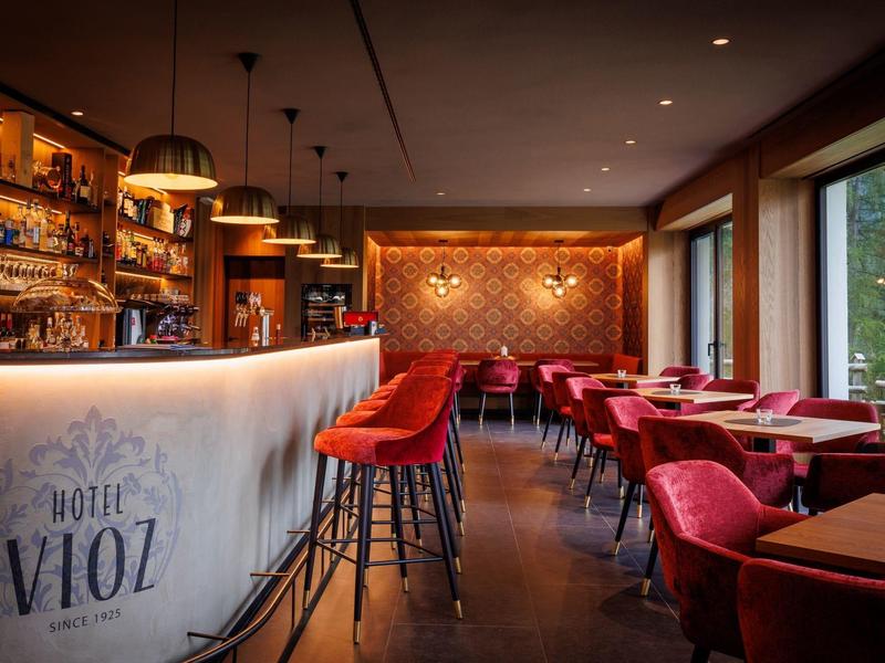 Bar d'hôtel confortable avec des chaises rouges, éclairage chaleureux et grande baie vitrée