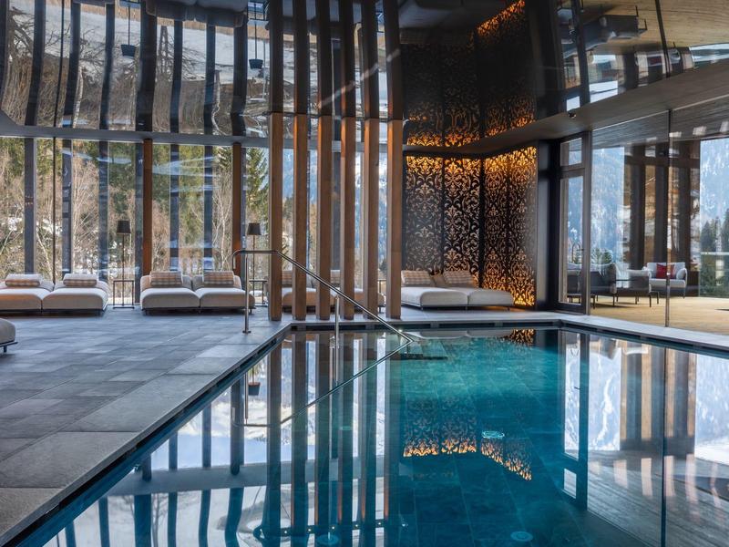 Piscine intérieure moderne avec lames en bois et chaises longues confortables dans un spa d'hôtel.
