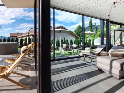 Moderne hotelkamer met open terrasdeur, uitzicht op zwembad en berglandschap op de achtergrond.