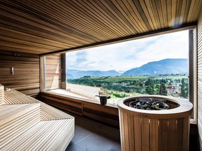 Moderne saunaruimte met houten interieur en panoramisch uitzicht op bergen en vallei.