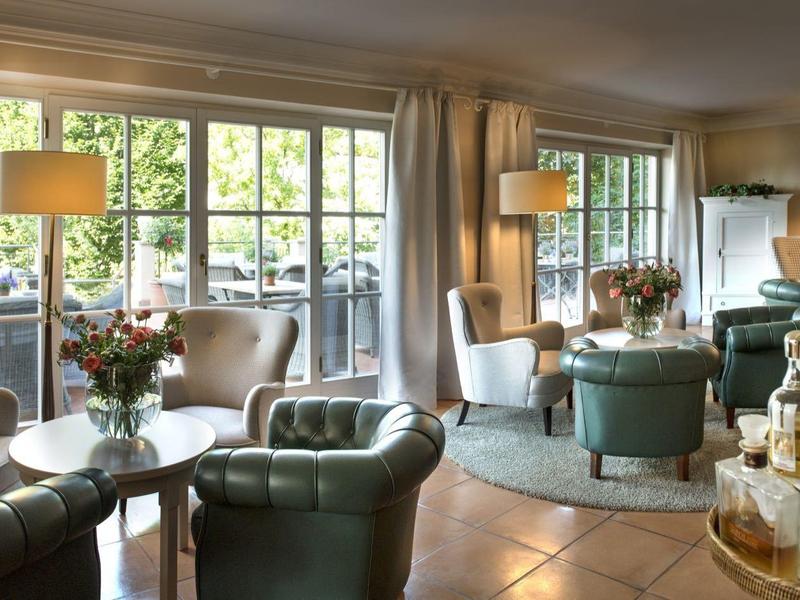 Salon élégant avec des fauteuils confortables, de grandes fenêtres et un bar élégant en arrière-plan.