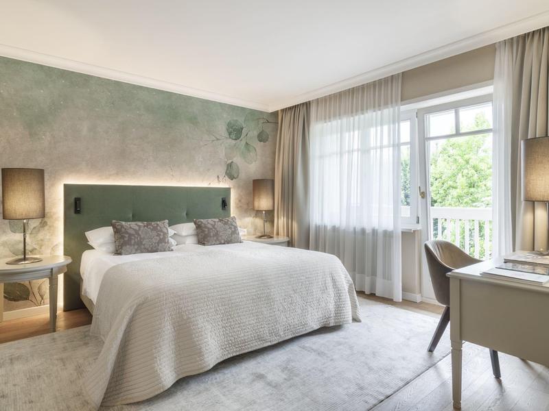 Chambre d'hôtel moderne avec grand lit, bureau et rideaux clairs.