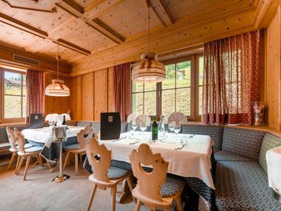 Gemütlicher Speiseraum mit Holzmöbeln und großen Fenstern in einem Hotel.