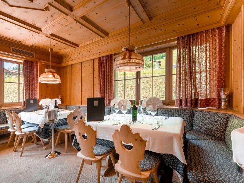 Gemütlicher Speiseraum mit Holzmöbeln und großen Fenstern in einem Hotel.