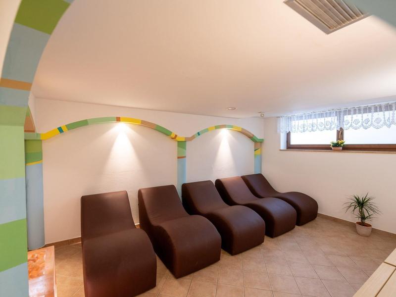 Eleganter Ruheraum mit braunen Liegesesseln, bunten Wandbögen und großen Fenstern.