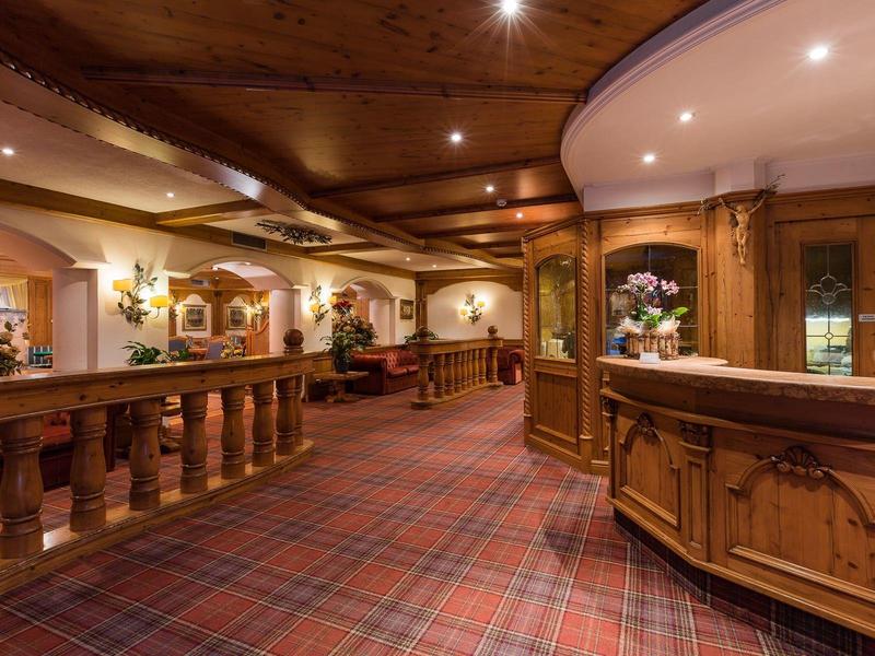 Przytulny korytarz hotelowy z drewnianą boazerią, wykładziną i recepcją z kwiatami.