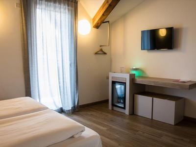 Chambre d'hôtel lumineuse avec lit double, télévision et balcon avec rideau.