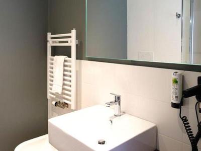 Salle de bain moderne avec lavabo blanc, toilettes et grand miroir sur mur gris.