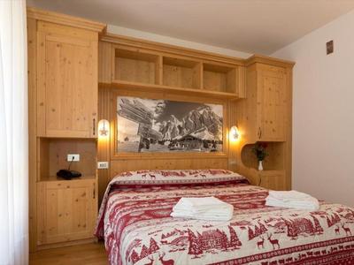 Gemütliches Schlafzimmer mit Doppelbett, Holzschrank und Bergbild an der Wand.