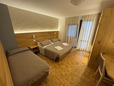 Camera d'hotel accogliente con due letti, mobili in legno e tende morbide alla finestra.