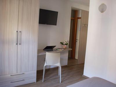 Blick auf einen Schreibtisch, Stuhl, Schrank und Fernseher in einem schlichten Hotelzimmer.