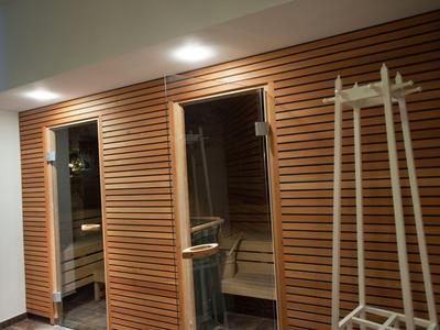 Moderner Saunabereich mit Holzwänden und Glastür, beleuchtet durch dezente Deckenlichter.