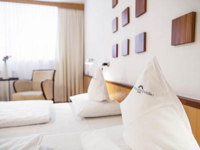 Hell eingerichtetes Hotelzimmer mit weißen Kissen und Holzdekoration an der Wand.