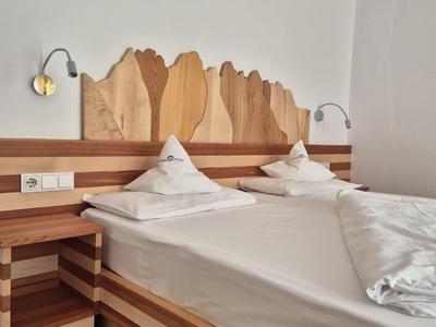 Ein schlichtes Hotelzimmer mit einem Doppelbett und Holzverkleidung an Kopf- und Fußteil.