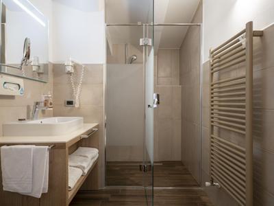Salle de bains moderne avec douche, lavabo, grand miroir et radiateur à serviettes.