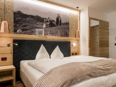 Chambre d'hôtel moderne avec décoration en bois, grand lit et lampes murales.