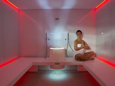 Une salle de détente moderne avec un éclairage d'ambiance rouge et une femme assise confortablement.