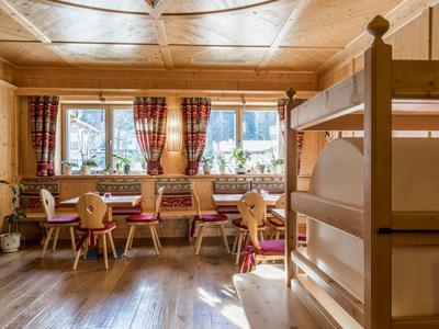 Auberge de montagne confortable avec meubles en bois, rideaux rouges et lits superposés.
