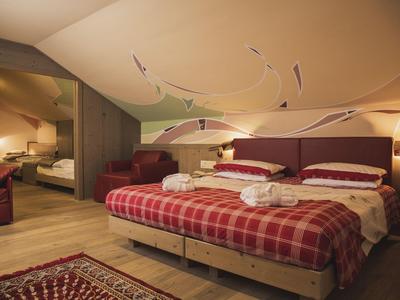 Gemütliches Hotelzimmer mit Doppelbett, roten Akzenten und Zugang zu einem angrenzenden Raum.