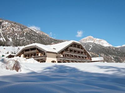 Ein großes Chalet in den Bergen mit Schnee bedeckt, klarer blauer Himmel im Hintergrund.