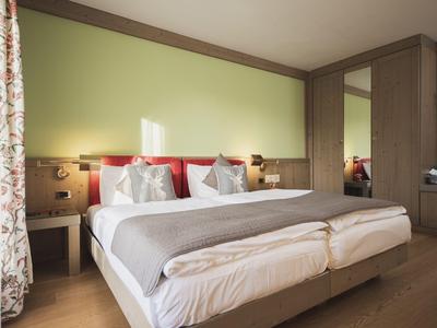 Modernes Hotelzimmer mit zwei Betten, grauem Bettbezug und grünlicher Wand