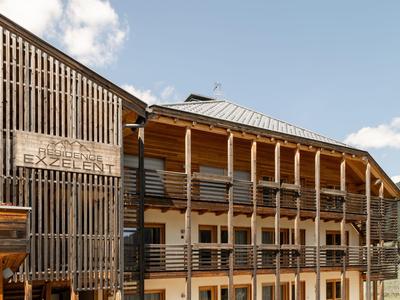 Hotelgebäude mit hölzerner Fassade und mehreren Balkonen unter blauem Himmel.