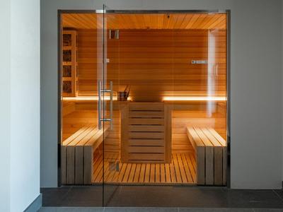 Moderne Sauna mit Holzwänden und Sitzbänken, durch eine Glastür sichtbar.