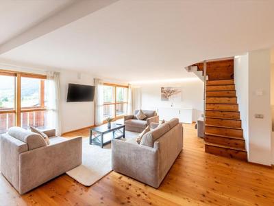 Helles Wohnzimmer mit Holzboden, grauen Sofas, Flachbildfernseher und Treppe aus Holz.