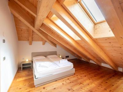 Modernes Schlafzimmer mit Holzbalken und Dachfenstern in einem Hotelzimmer.