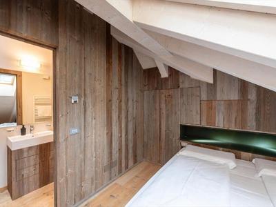 Gemütliches Schlafzimmer mit Dachschräge, Holzwänden und modernem Waschbecken.