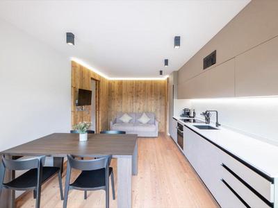 Moderner Hotelraum mit Küchenzeile, Esstisch und gemütlichem Doppelbett in warmem Holzdesign.