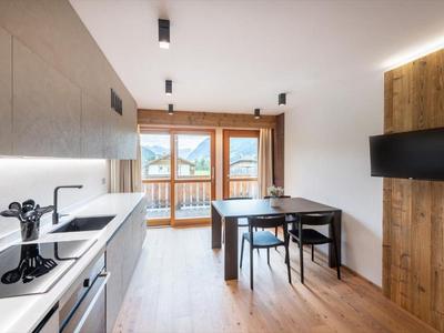 Helle Küchenecke mit Esstisch, Stühlen und Balkon mit Bergblick in einem Hotelzimmer.