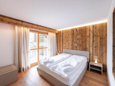 Helles Hotelzimmer mit Holzverkleidung, Doppelbett und Fenster mit Vorhängen.