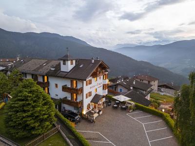 Hotelgebäude in bergiger Landschaft mit Terrassen und Parkplatz bei wolkigem Himmel.