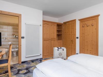 Hotelzimmer mit Doppelbett, Holzmöbeln, Flachbildfernseher und Badezimmer mit Dusche.