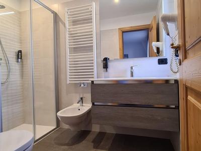 Modernes Badezimmer mit Duschkabine, Waschtisch, Bidet und Handtuchheizkörper im Hotelzimmer.