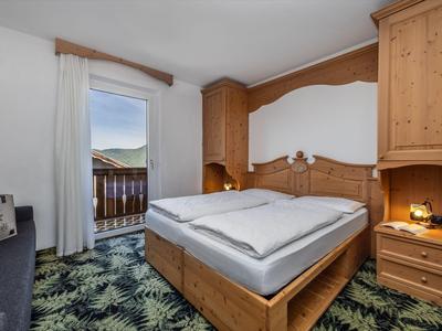 Gemütliches Schlafzimmer mit Holzmöbeln und Balkon mit Bergblick.