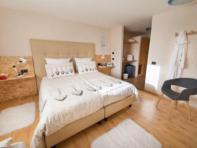 Hell eingerichtetes Hotelzimmer mit Doppelbett, Holzboden und modernem Mobiliar.