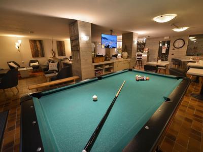 Ein stilvoll eingerichteter Hotelspielraum mit einem grünen Billardtisch und bequemen Sitzmöglichkeiten.