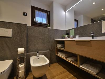 Modernes Badezimmer mit Bidet, Toilette, Holzregal und Spiegel im Hotel.