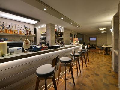 Moderner Hotelbarbereich mit Holzbar, Barhockern und warmem Lichtdesign.