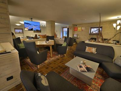 Gemütlicher Hotel-Loungebereich mit Sesseln, Sofas und warmem Holzdekor.