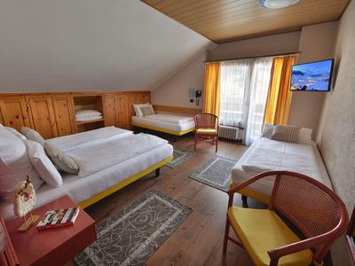 Gemütliches Schlafzimmer mit drei Betten, Holzverkleidung und Balkon mit Blick.